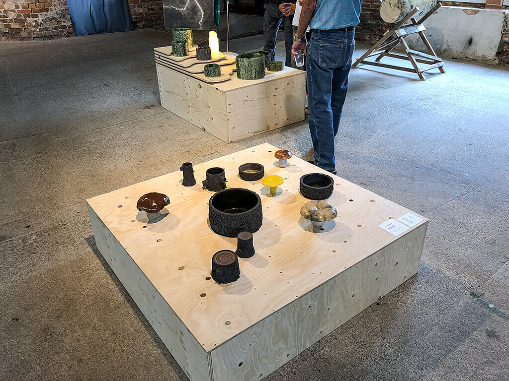 Fotografi från Ånghammaren 2018 på skulpturer skapad av Ulf Samuelsson. Flera skulpturer som formas likt skålar men dekoreras med bark textur på utsidan  tillsammans med skulpturer som liknar svampar.